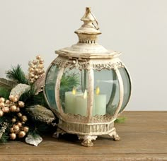 two lit candles are sitting on a table next to christmas greenery and pine cones