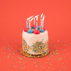 a birthday cake with white frosting and colorful sprinkles on red background