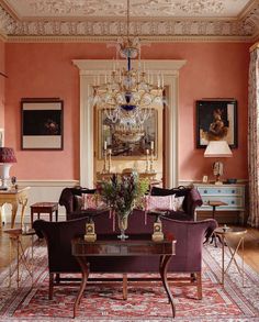 a living room filled with furniture and a chandelier hanging from the ceiling over a table