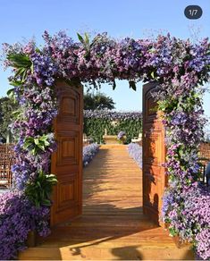 an open wooden door with purple flowers growing on it's sides and in the middle