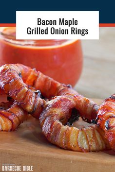 bacon wrapped pretzels sitting on a cutting board next to a jar of tomato sauce