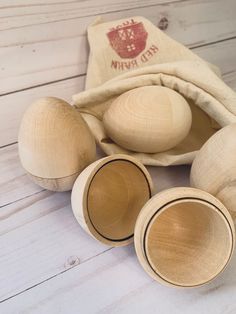 three wooden bowls and two spoons on a white wood floor with a bag in the background