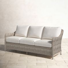 a white couch sitting on top of a tile floor next to a wall and window