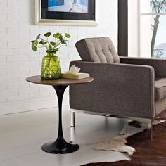 a living room with a chair, table and potted plant