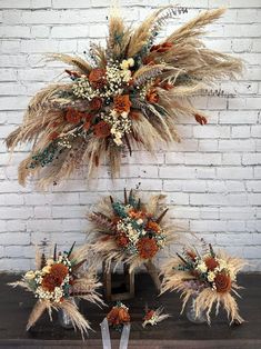 two bouquets with dried flowers and feathers on display in front of a brick wall