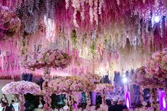 people are standing under pink flowers hanging from the ceiling