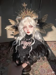 a woman with white hair wearing a black dress and gold headdress is sitting on a couch