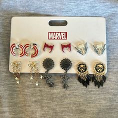 there are many different earrings in the package on the table, including captain america and iron man