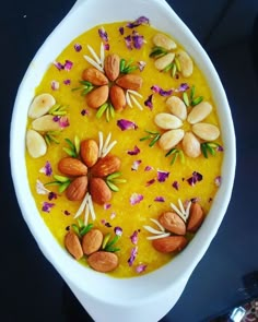 a white bowl filled with nuts and flowers on top of a table next to a spoon