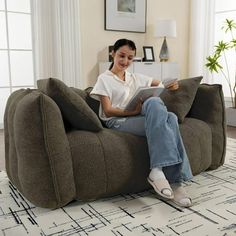 a woman is sitting on a bean bag chair and reading a book in her living room