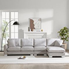 a living room with white walls and wooden floors, a large sectional couch in the middle