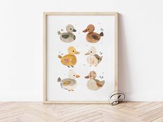 an art print with ducks on it in a wooden frame against a white wall and wood floor