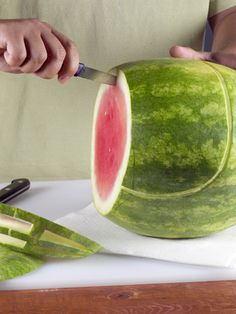 a person cutting up a watermelon with a knife