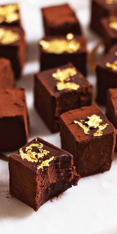 several pieces of chocolate cake with gold leaf decorations on them sitting on a white surface