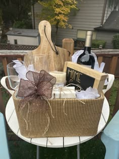 a basket with wine, cheese and other items on top of a metal table in front of a house