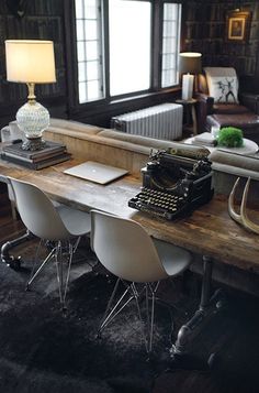 an old fashioned desk with three chairs and a typewriter on it