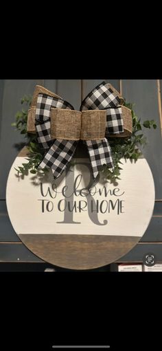 a wooden sign that says welcome to our home with a large bow on the front