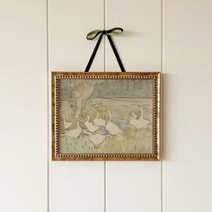 a painting hanging on the wall with a bow around it's neck and two geese