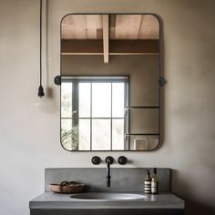 a bathroom sink under a large mirror next to a wall mounted faucet and light fixture