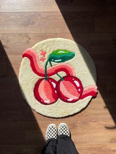 a person standing in front of a rug with cherries on it and the floor