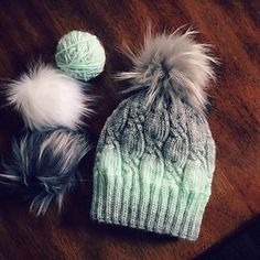 two hats are sitting on a table next to each other with pom - poms