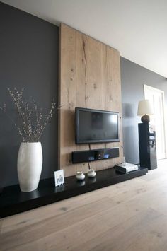 a living room with a flat screen tv mounted on the wall next to a large white vase