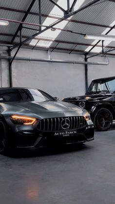 two mercedes benz amg vehicles parked in a garage, one is black and the other is silver