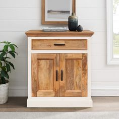 a wooden cabinet sitting next to a potted plant