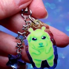 a hand holding a keychain with a green dog on it