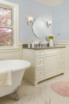 a white bath tub sitting under a bathroom mirror