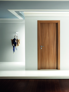 an empty room with a wooden door and coat rack