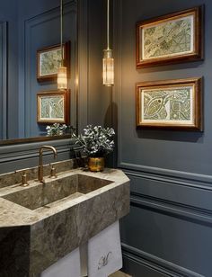 a bathroom sink sitting under two framed pictures