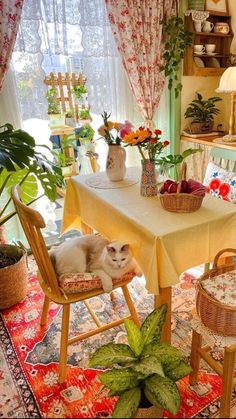 an image of a cat sitting on a chair in front of a table with flowers