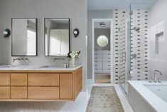 a large bathroom with two sinks and a bathtub in the middle, along with mirrors on the wall