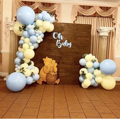 winnie the pooh balloon arch with blue and yellow balloons in front of an entrance