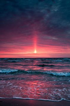 the sun is setting over the ocean with waves coming in to shore and pink clouds