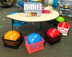 several plastic balls and baskets sit on the floor in front of a table with chairs