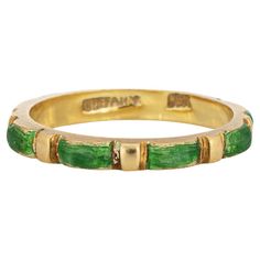 Vintage Tiffany & Co green enamel ring crafted in 18 karat yellow gold (circa 1970s to 1980s). Green enameled panels are continuous around the band for a seamless look. The enamel is in fair condition with enamel loss present. The slim 2.5mm wide band (0.09 inches) is great worn alone or stacked with your fine jewelry from any era. The ring is in fair condition. We have not cleaned it in order to preserve the patina and collector value. Particulars: Weight: 2.8 grams Stones: N/A Size & Measurements: The ring is a size 5 (not sizable). The band measures 2.5mm wide (0.09 inches), rising 3mm from the finger. Metal & Hallmark: 18 yellow gold. The ring is hallmarked "18k" and "Tiffany" Hallmarked Green Enamel Ring For Anniversary, Vintage Yellow Gold Enamel Rings, Vintage Yellow Gold Enamel Ring For Ceremonial Occasions, Green Hallmarked Enamel Ring For Anniversary, Yellow Gold Enamel Ring Stamped 14k, Classic Green Enamel Jewelry, Modernist Green Rings For Anniversary, Green Modernist Rings For Anniversary, Formal Green Enamel Ring With Polished Finish