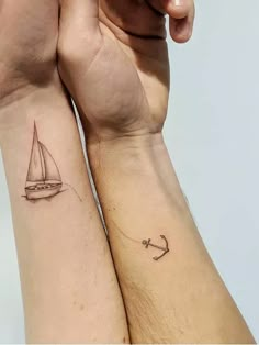 two people with matching tattoos holding each other's hands and one has an anchor on it