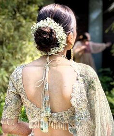 the back of a woman's dress with flowers in her hair and an elaborate headpiece