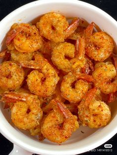 a white bowl filled with cooked shrimp on top of a table