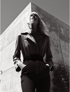 a black and white photo of a woman standing in front of a building with her hands on her hips