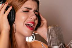 a woman with headphones on singing into a microphone