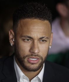 a close up of a person wearing a suit and tie with an earring on