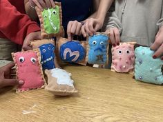 some people are making small stuffed animals out of felt and paper machs on a table