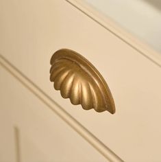 a close up of a gold door handle on a white cabinet