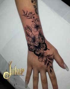 a woman's hand with a butterfly tattoo on it and flowers around the wrist