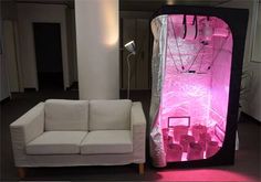 a white couch sitting next to a pink light filled room