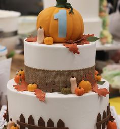 a three tiered cake decorated with pumpkins and leaves