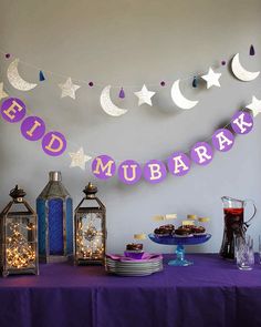 a purple table topped with lots of food next to lanterns and stars hanging from the ceiling